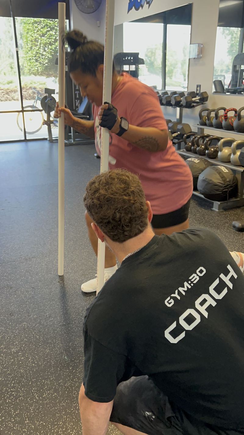 A GYM:30 coach guiding a member through a mobility drill
